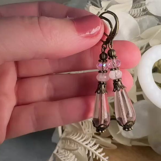 These beautiful Victorian earrings are handmade with rose quartz stones, lustrous pink Czech glass teardrop beads, and faceted crystals. These whimsical blushing rose earrings feature a delightful mix of soft pink hues and rustic bronze detailing. A wonderful pair of earrings for elegant everyday wear. video