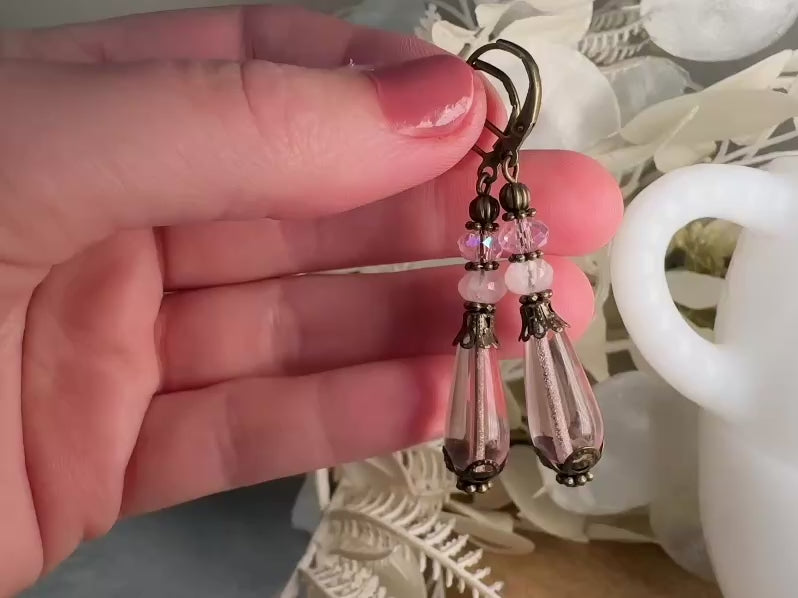These beautiful Victorian earrings are handmade with rose quartz stones, lustrous pink Czech glass teardrop beads, and faceted crystals. These whimsical blushing rose earrings feature a delightful mix of soft pink hues and rustic bronze detailing. A wonderful pair of earrings for elegant everyday wear. video