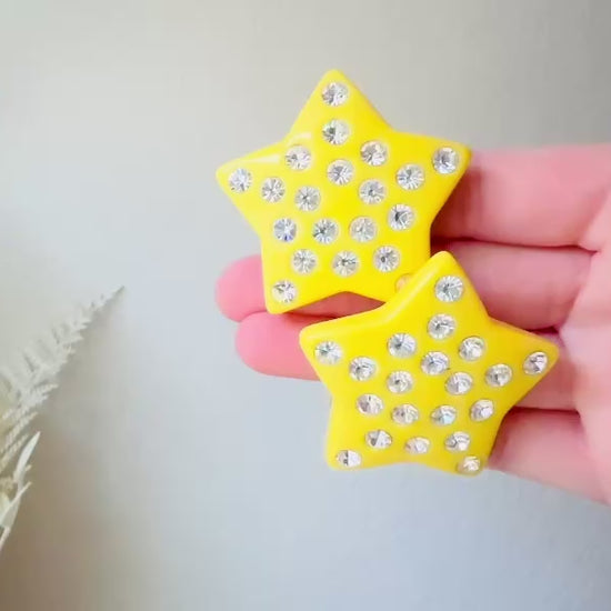 A pair of yellow star earrings from Piggle and Pop. A highly collectible pair of 1980s statement earrings. These yellow star earrings are bright banana yellow opaque lucite with diamond rhinestone accents. Huge vintage star clip ons with major rockstar vibes. Video