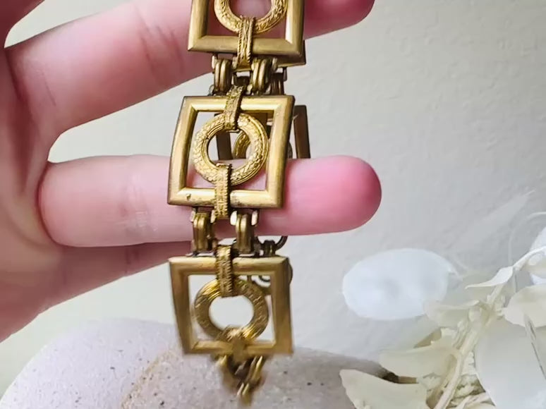 This is a vintage square link bracelet composed of antique gold geometric links. Featuring five structured squares with a floral embossed circle ring inside each one. This bold 1970s vintage chain bracelet is so unique; the circle inside of square and contrast of the bold shape with the royal floral motif is so interesting. It is 7 inches long in great vintage condition. Video