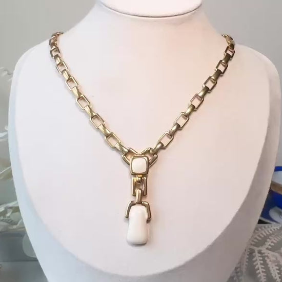 This vintage gold chain Y necklace by Monet is a rare find. Featuring flat link cable chain with a geometric drop pendant with cream enamel accents. This signed vintage necklace is from the 1970s at a peak time for Monet designs. This classic necklace is in excellent condition and just as classic today as it was when it debuted. Adjustable length with a hook closure.  video