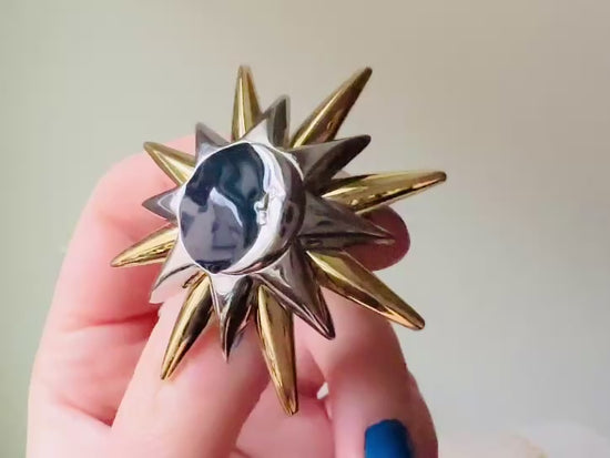 Video of a vintage Liz Claiborne moon and starburst brooch from the 1980s. In excellent condition, this pin features a silver and gold starburst with a silver crescent moon on top of black circular enamel inlay. High quality designer signed brooch. No flaws to note, this vintage brooch has a fully working pin and lock, in great condition.