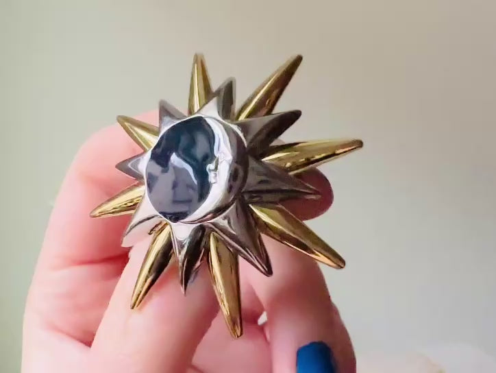 Video of a vintage Liz Claiborne moon and starburst brooch from the 1980s. In excellent condition, this pin features a silver and gold starburst with a silver crescent moon on top of black circular enamel inlay. High quality designer signed brooch. No flaws to note, this vintage brooch has a fully working pin and lock, in great condition.