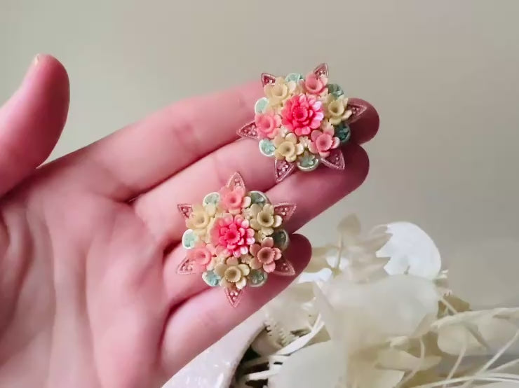 Video of vintage 1950s Japanese floral celluloid earrings are so colorful. Carved celluloid bursting with sakura blossoms and flowers, these earrings are on the larger side and are painted with a beautiful pearlized pink, blue and light cream. The star-shaped base and raised beaded edges are also characteristic of vintage Japanese celluloid jewelry. They are 1.5" in size.