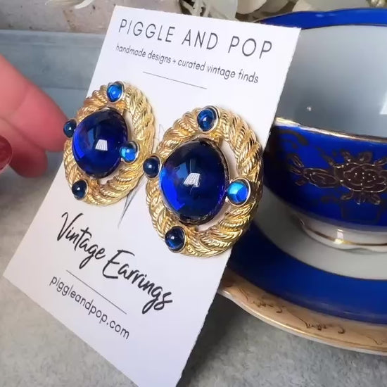 These vintage Park Lane gold rope earrings with cobalt blue cabochons are absolutely out of this world! Vibrant deep blue cabochons glow as they are surrounded by an intricate gold rope border that is accented with four more smaller blue jewels. These stones are so vibrant and vividly pop against their gold setting. Ultimate 80s mega star vibes, post style for pierced ears. Highly collectible signed designer pair in excellent vintage condition, no major flaws to note. video