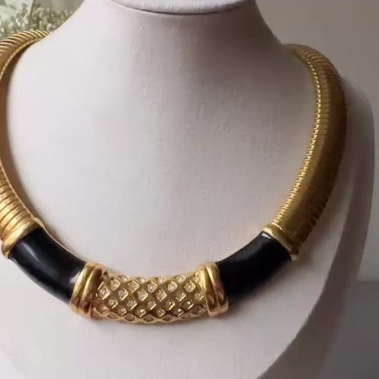 This vintage omega necklace is a stunning black and gold Monet designer vintage necklace. Featuring wide band snake chain and geometric segments of black enamel. This 1980s vintage rhinestone collar necklace has a fold over clasp and extender link. &nbsp;Excellent condition. This vintage designer necklace is high quality, weighty and well made. Video.