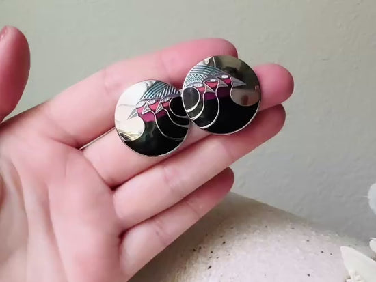 A pair of Laurel Burch vintage earrings titled  "Celestial Birds". These post earrings are shiny silver with black and plum pink enamel of three birds lined up in a side profile. Laurel Burch is highly collectible, and these are so unique. Engraved with the the title "Celestial Birds" on the back of earrings along the the signature on the backs. Silver plated posts, excellent condition with very minor wear. They are about 1 inch big and available from Piggle and Pop. Video of earrings.
