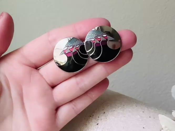 A pair of Laurel Burch vintage earrings titled  "Celestial Birds". These post earrings are shiny silver with black and plum pink enamel of three birds lined up in a side profile. Laurel Burch is highly collectible, and these are so unique. Engraved with the the title "Celestial Birds" on the back of earrings along the the signature on the backs. Silver plated posts, excellent condition with very minor wear. They are about 1 inch big and available from Piggle and Pop. Video of earrings.