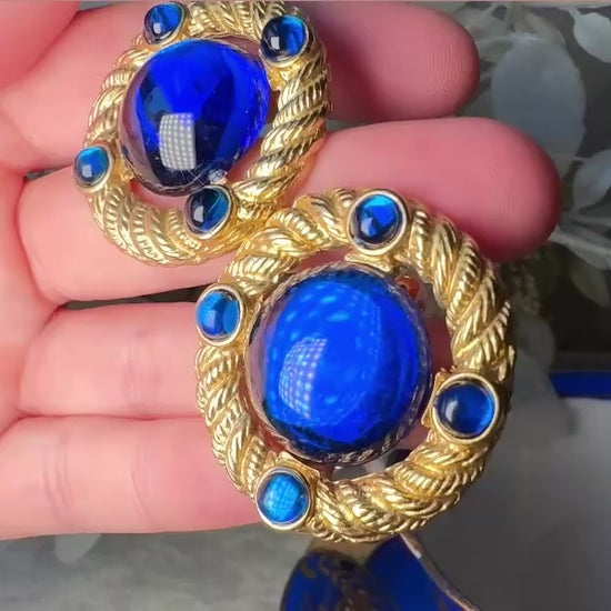 These vintage Park Lane gold rope earrings with cobalt blue cabochons are absolutely out of this world! Vibrant deep blue cabochons glow as they are surrounded by an intricate gold rope border that is accented with four more smaller blue jewels. These stones are so vibrant and vividly pop against their gold setting. Ultimate 80s mega star vibes, post style for pierced ears. Highly collectible signed designer pair in excellent vintage condition, no major flaws to note. video of details.