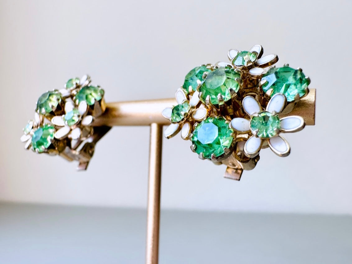 Close up of Vintage green rhinestone and white enamel flower clip  on earrings by Weiss from Piggle and Pop