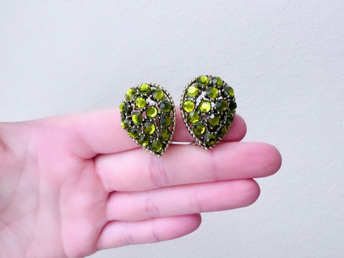 Green Teardrop rhinestone earrings held in hand for size reference