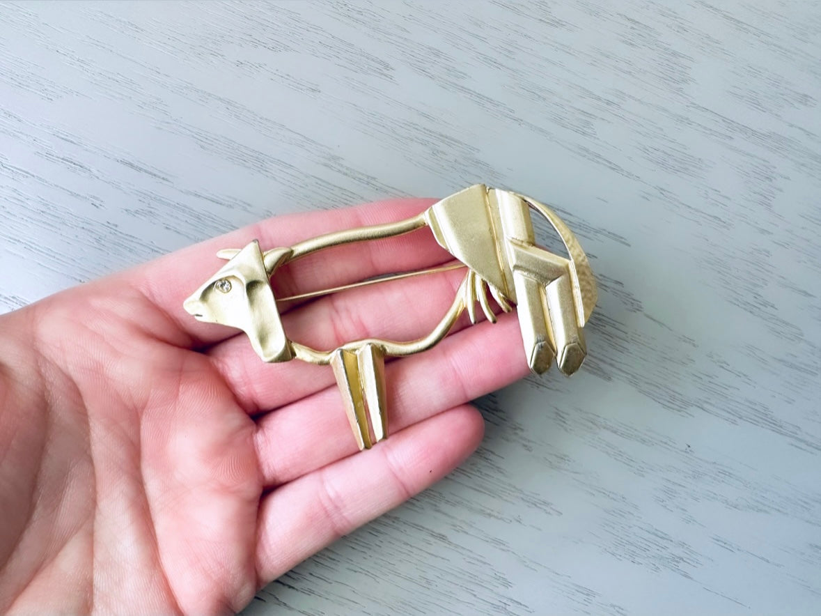 hand holding a vintage gold Abstract Cow Brooch for size reference